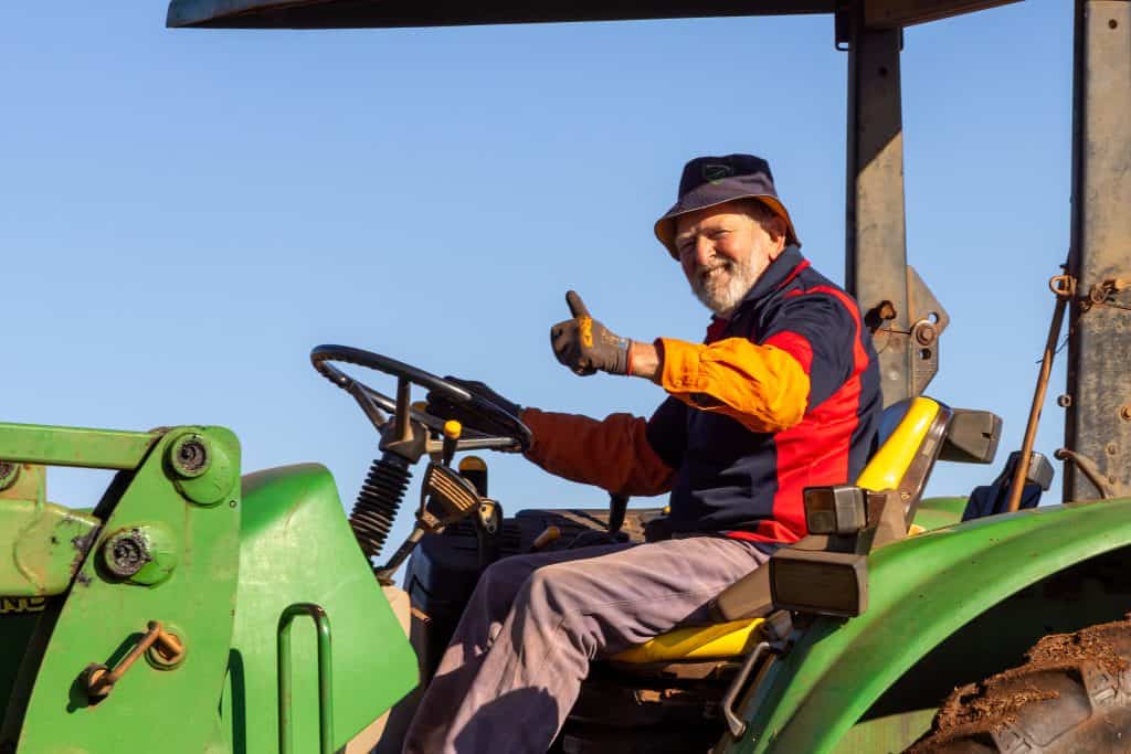 Experienced farmer operating green tractor outdoors.